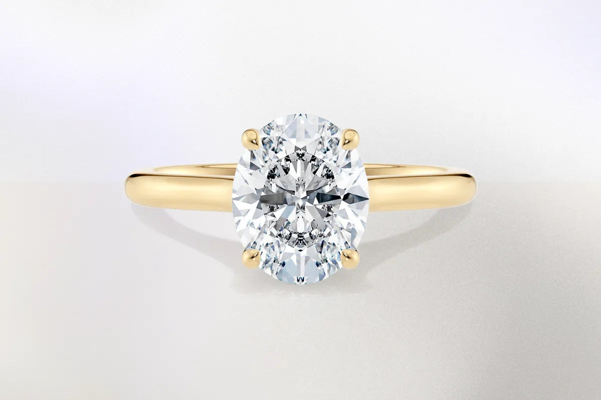 Oval diamant i klassisk enstensinnfatning av gult gull. Illustrerer hvordan ovale diamanter gir størrelsesillusjon og elegant form