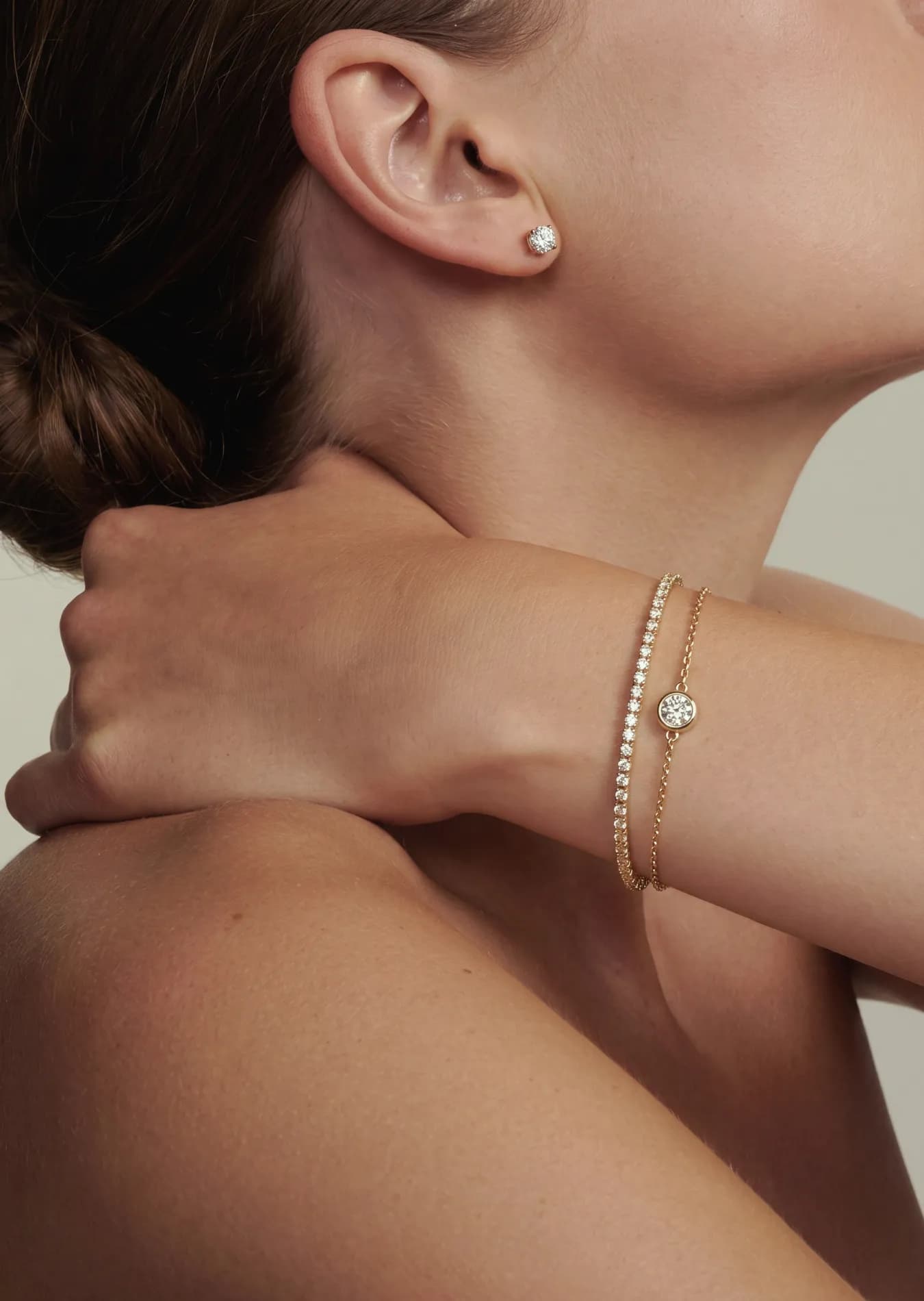 Modell med tennisarmbånd og diamantarmbånd i gult gull rundt håndleddet