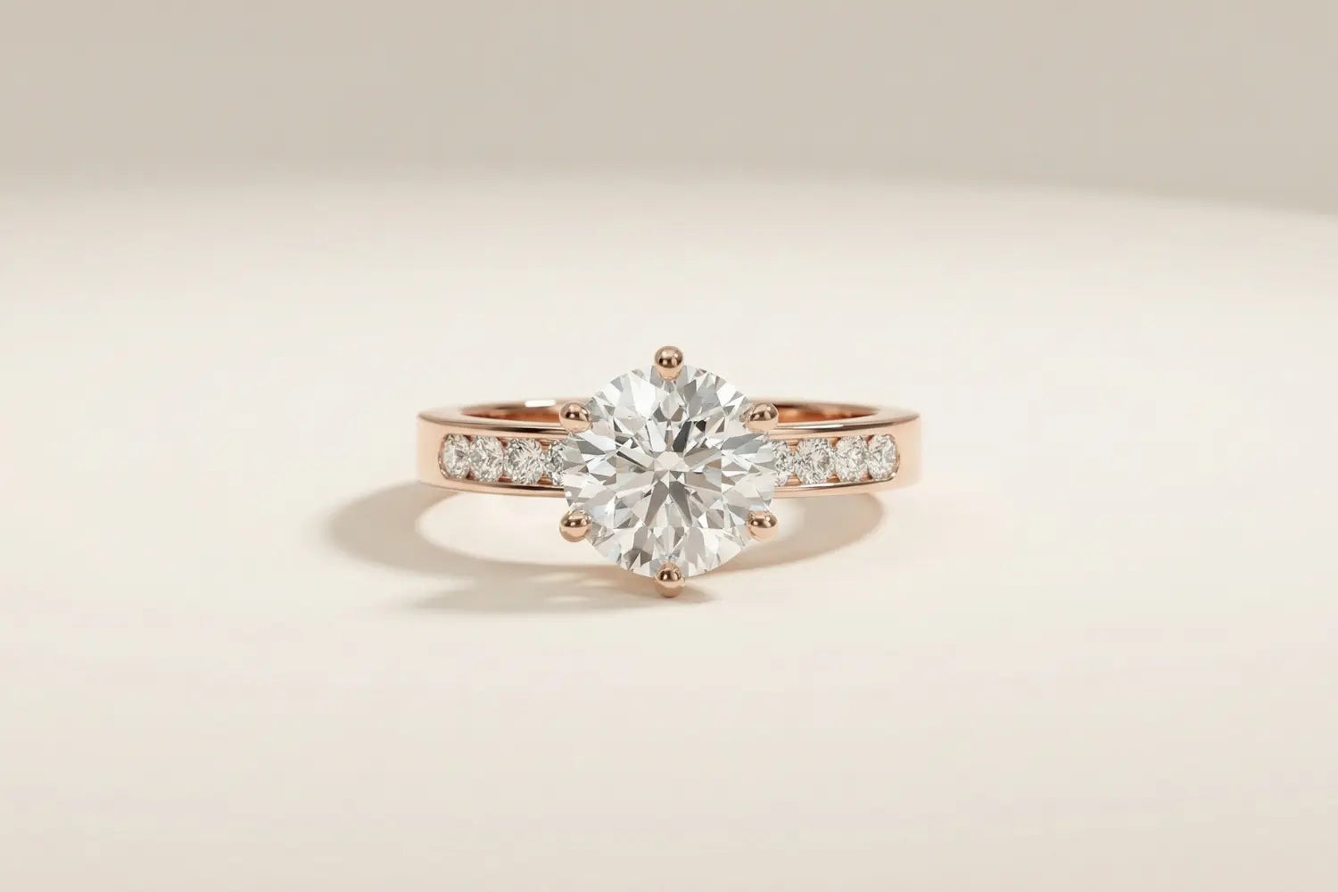 Diamantring i roségull med kanalinnfattede lab diamanter på skinnen og diamant i klør i senter