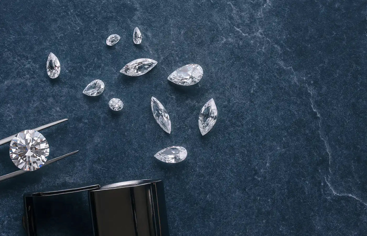 Ekte diamanter i ulike slipformer på lys lilla bakgrunn – illustrerer hvordan man kan se om en diamant er ekte.