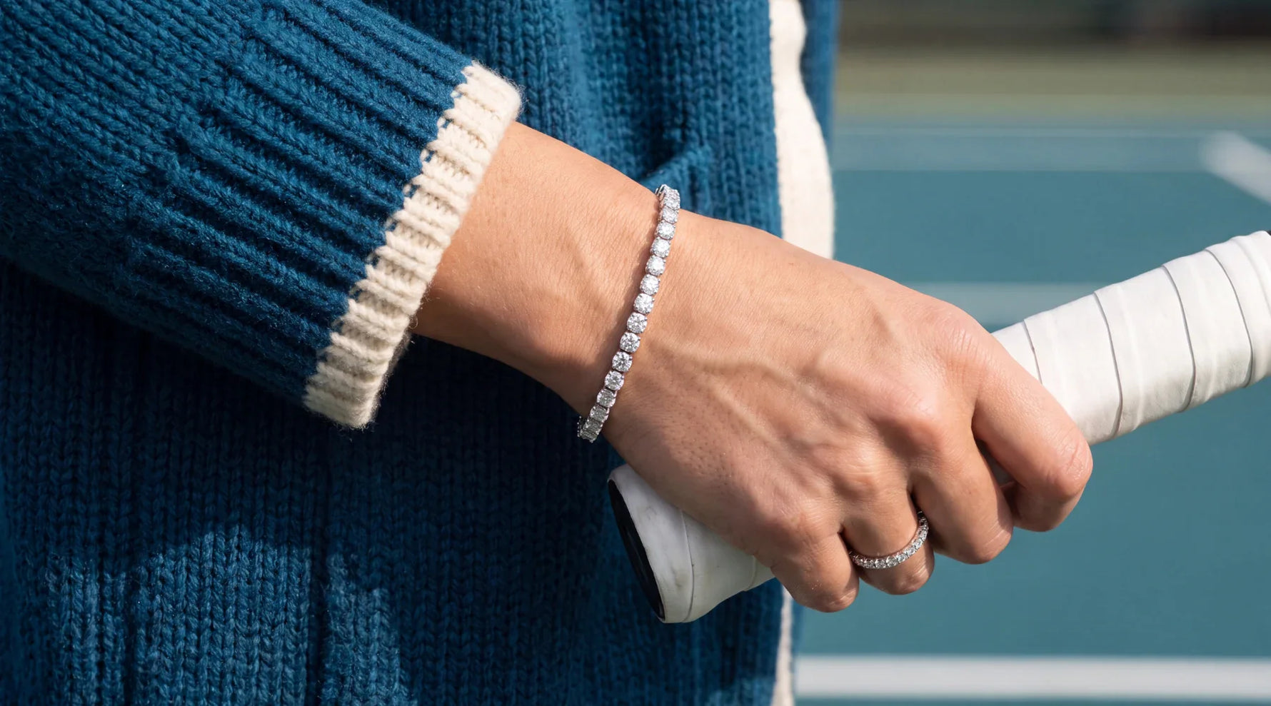 Kvinne holder en tennisrekkert og har på seg et 8 carat tennisarmbånd i hvitt gull 