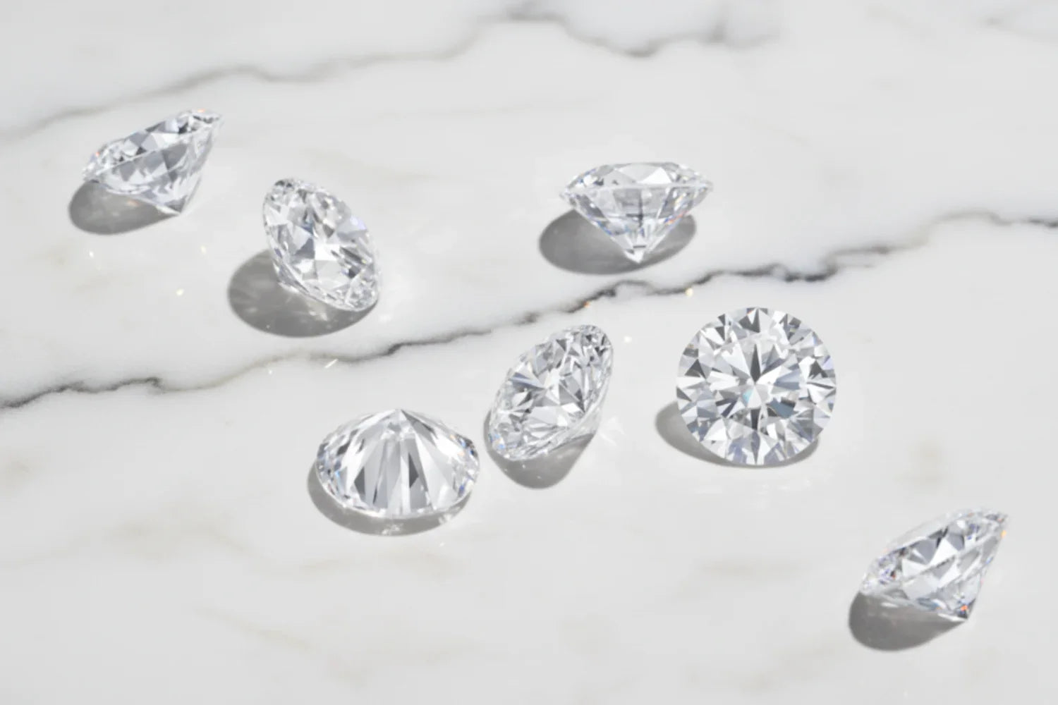 Flere diamanter liggende på en marmorplate – illustrasjon til guide om hvordan kjøpe diamant på nett trygt og ekte