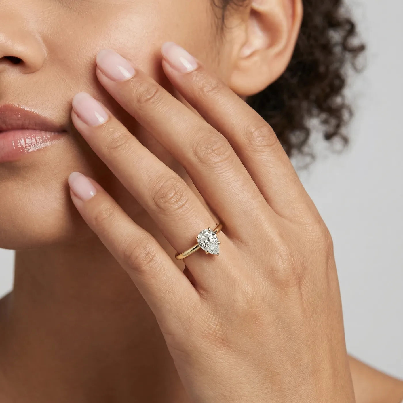 Diamantring i gult gull med 1 carat dråpe-formet lab diamant vist på modell i naturlig lys