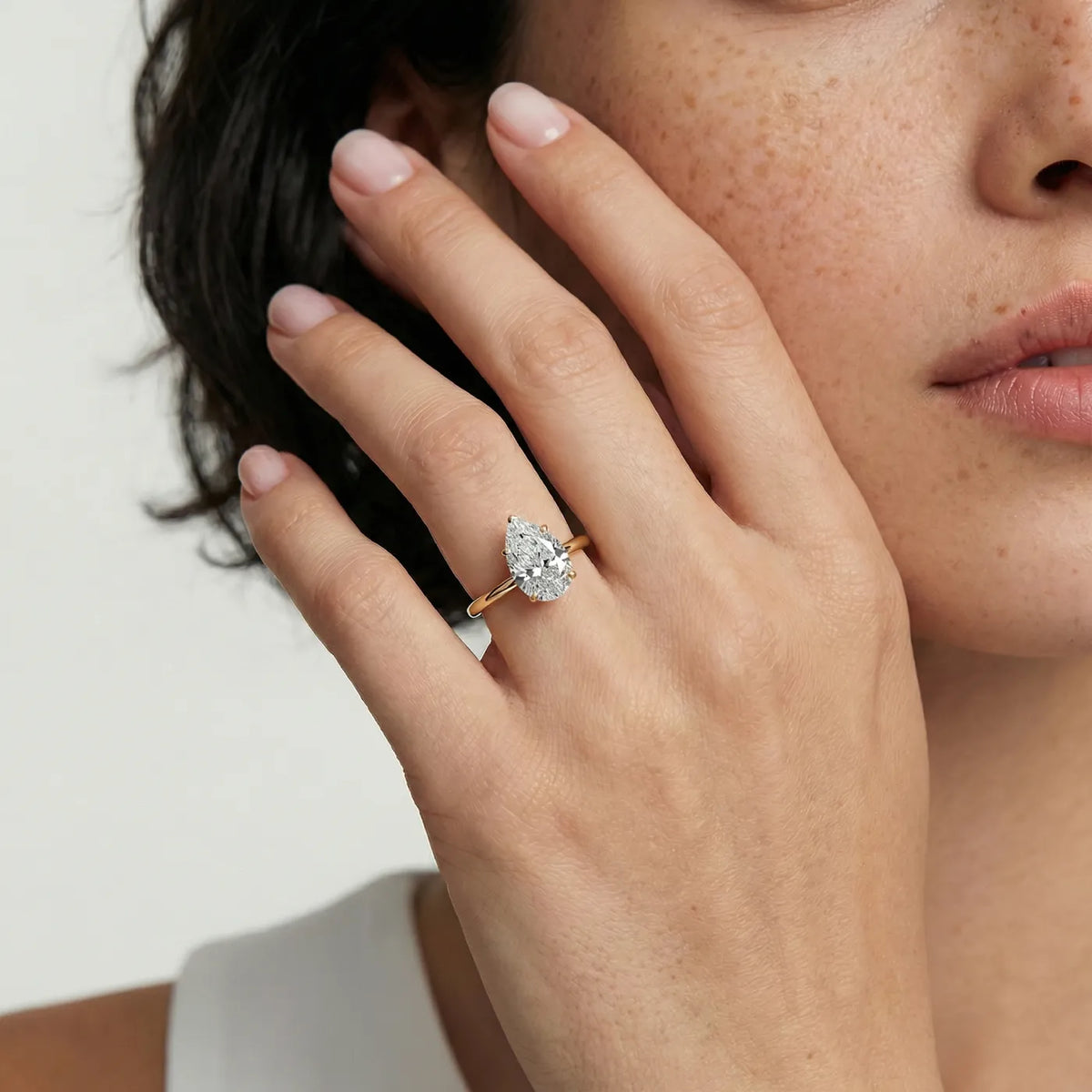 Diamantring i gult gull med 2 carat dråpe-formet lab diamant vist på modell i naturlig lys