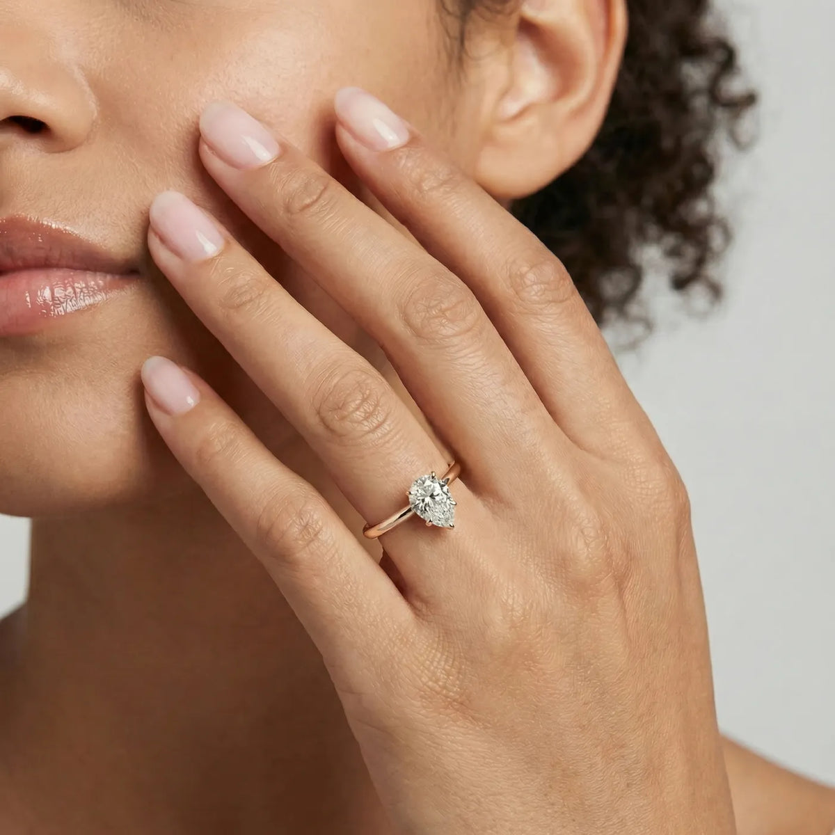 Diamantring i rosegull med 1 carat dråpe-formet lab diamant vist på modell i naturlig lys