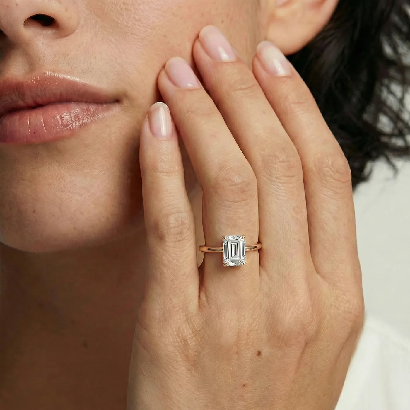 1 carat emerald cut diamantring i rosegull med lab diamant vist på modell i naturlig lys