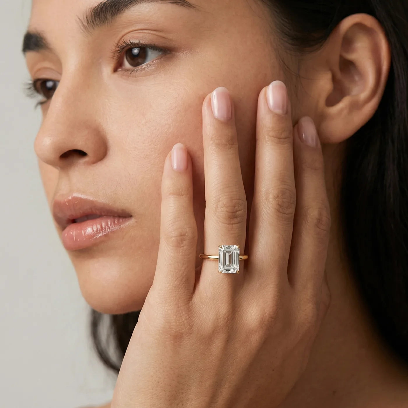 2 carat emerald cut diamantring i gult gull med lab diamant vist på modell i naturlig lys