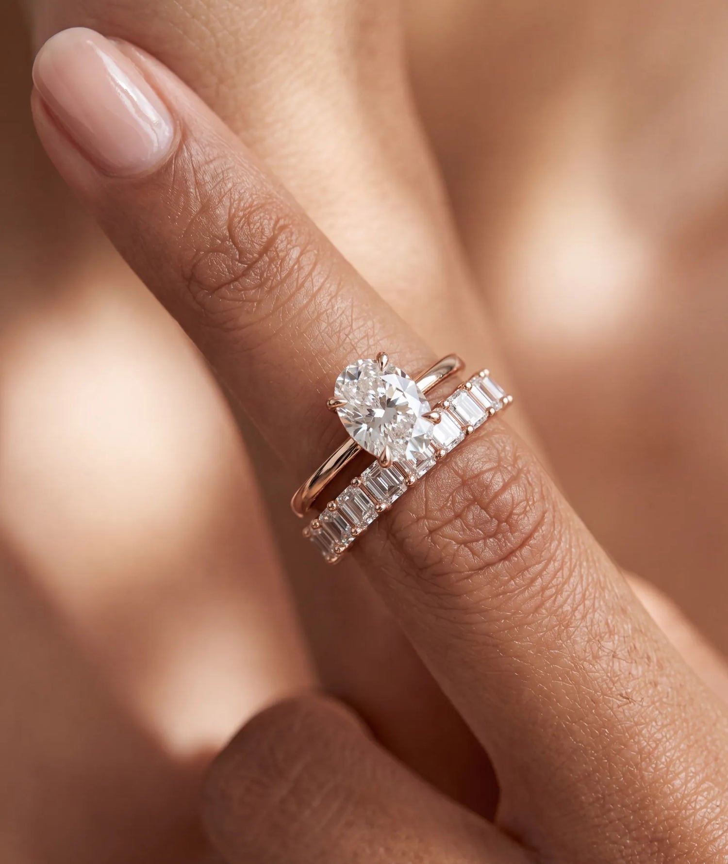 Oval diamantring i rosegull 1 arat diamant på finger sammen med en alliansering i rosegull med emerald cut diamanter 