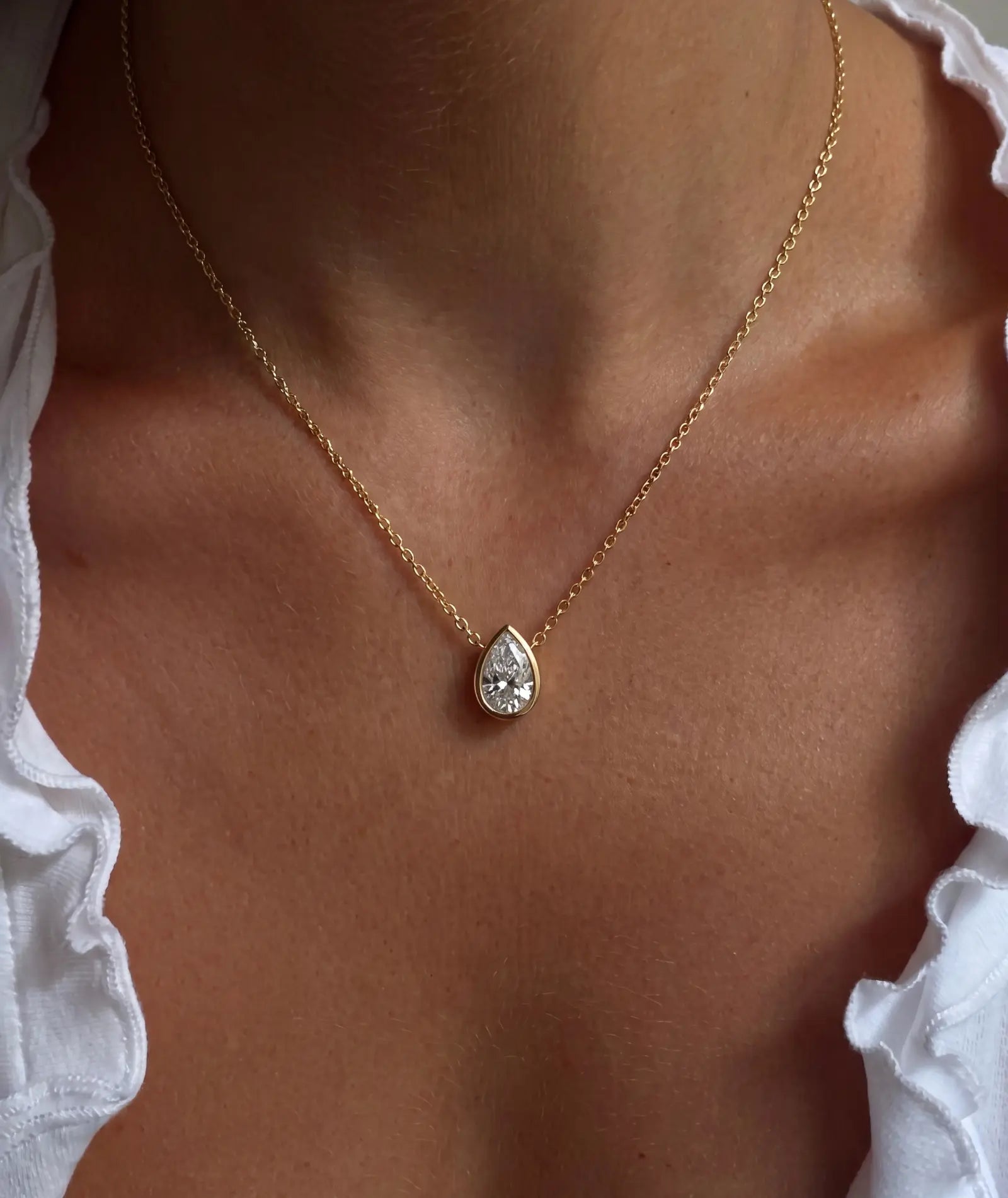 Dråpeformet diamanthalskjede i bezelinnfatning, 14K gult gull på modell.
