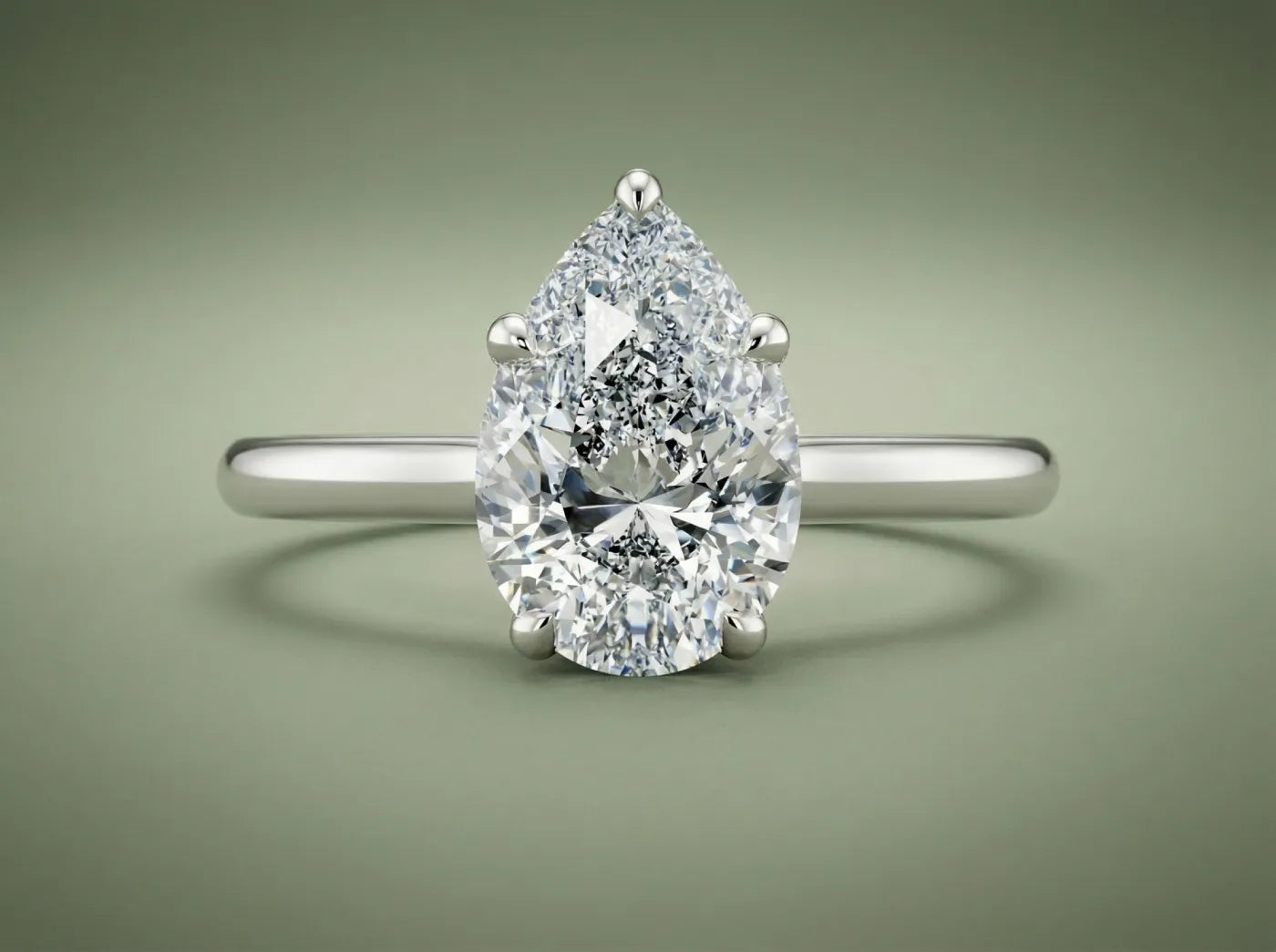 dråpeformet lan diamant i en hvitt gull forlovelsesring med grønn bakgrunn som symbol på bevist luksus