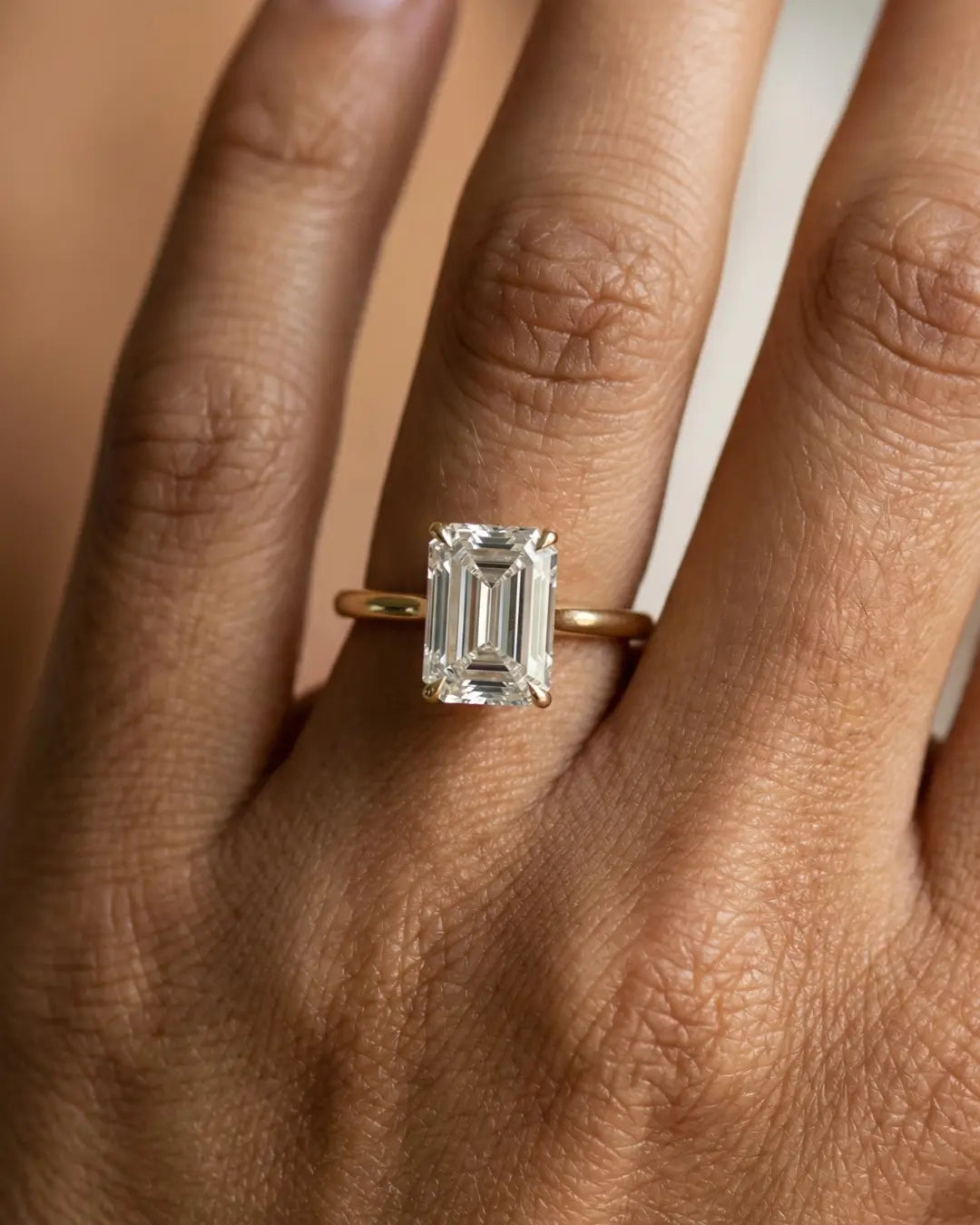 2 carat emeraldcut diamantring i gult guill på hånden til modell 
