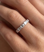 Emerald cut east-west eternity-ring i bezelinnfatning, 14K hvitt gull, nærbilde på finger, 1,40 ct laboratoriedyrkede diamanter.