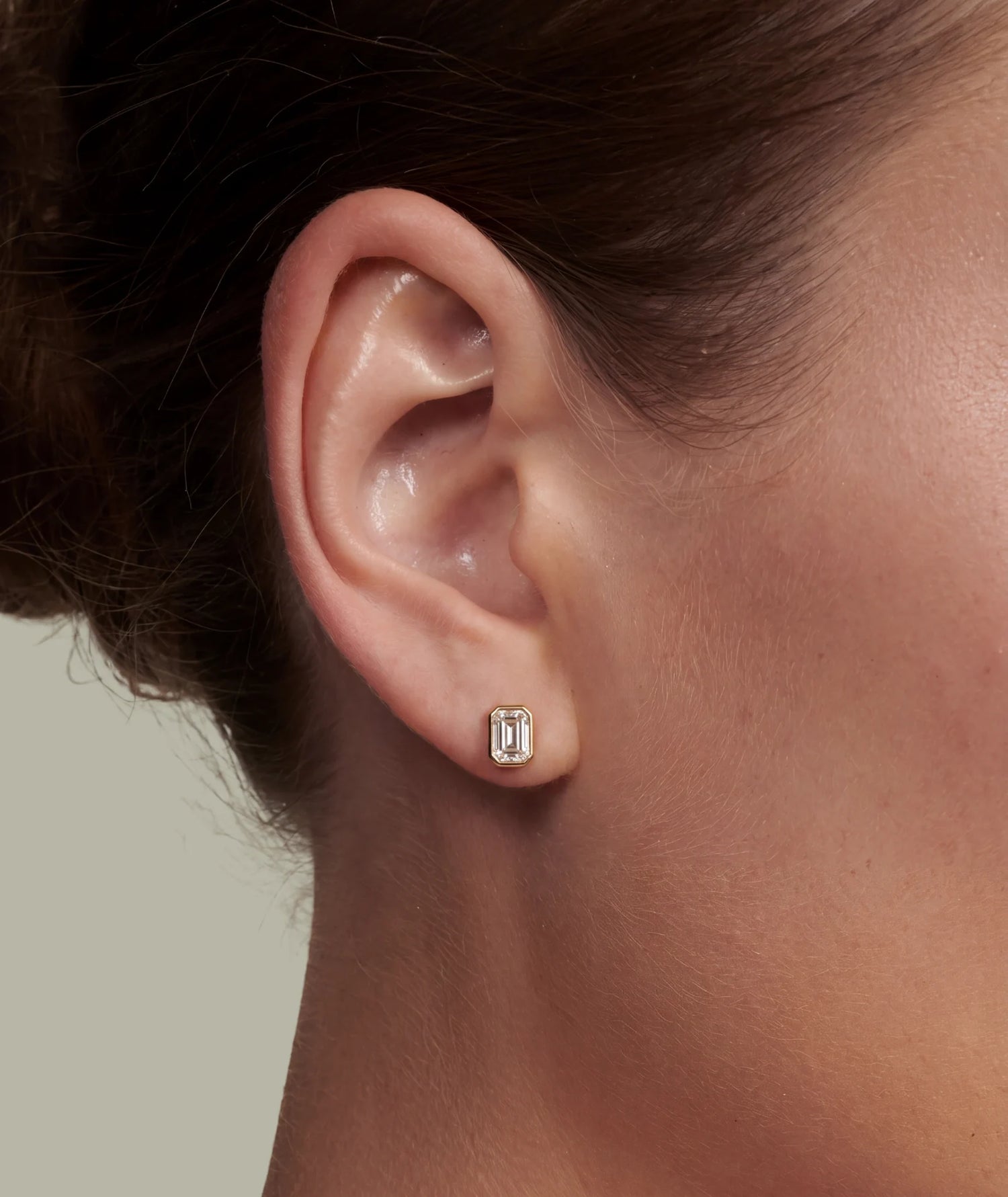 Emerald cut enstensøredobb i bezel innfattning i øret på modell.