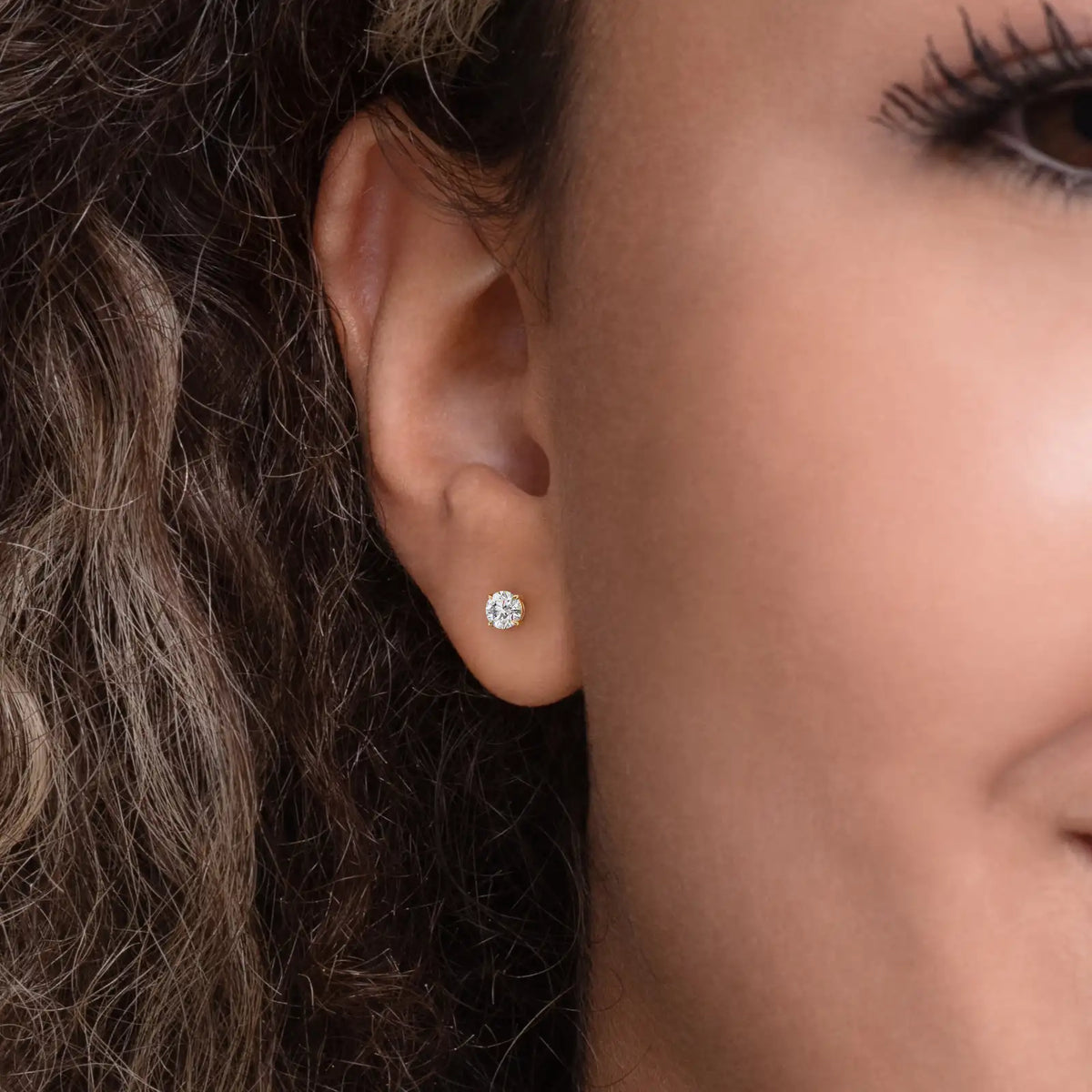 Enstens diamantøredobb i gult gull 0,60 ct med fire klør – vist i øret på modell.