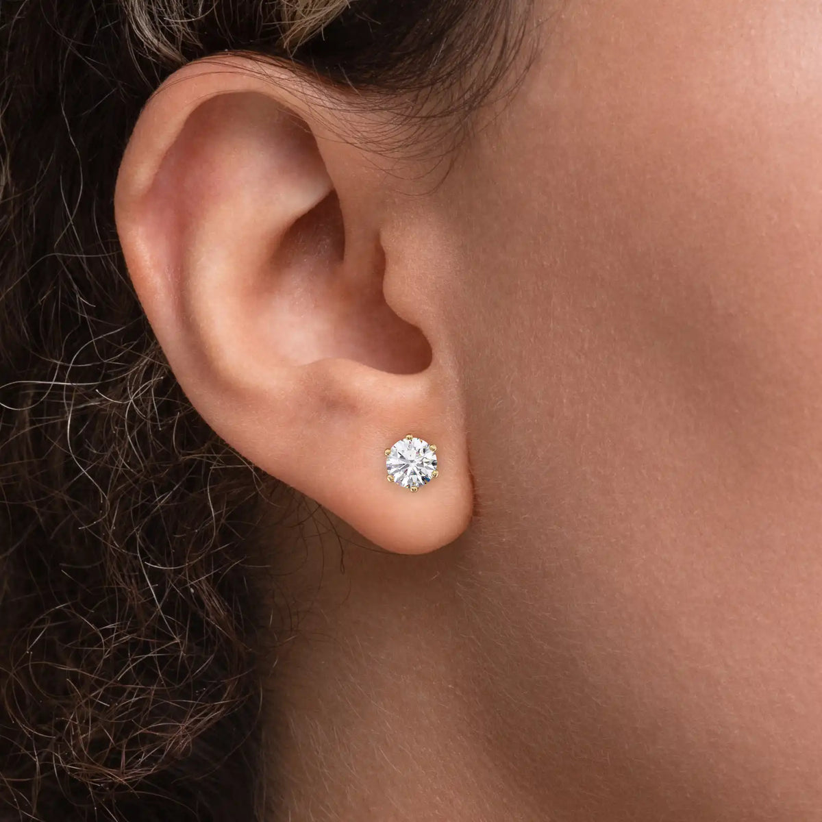 Enstens diamantøredobb i gult gull 2,00 ct med seks klør – vist i øret på modell.