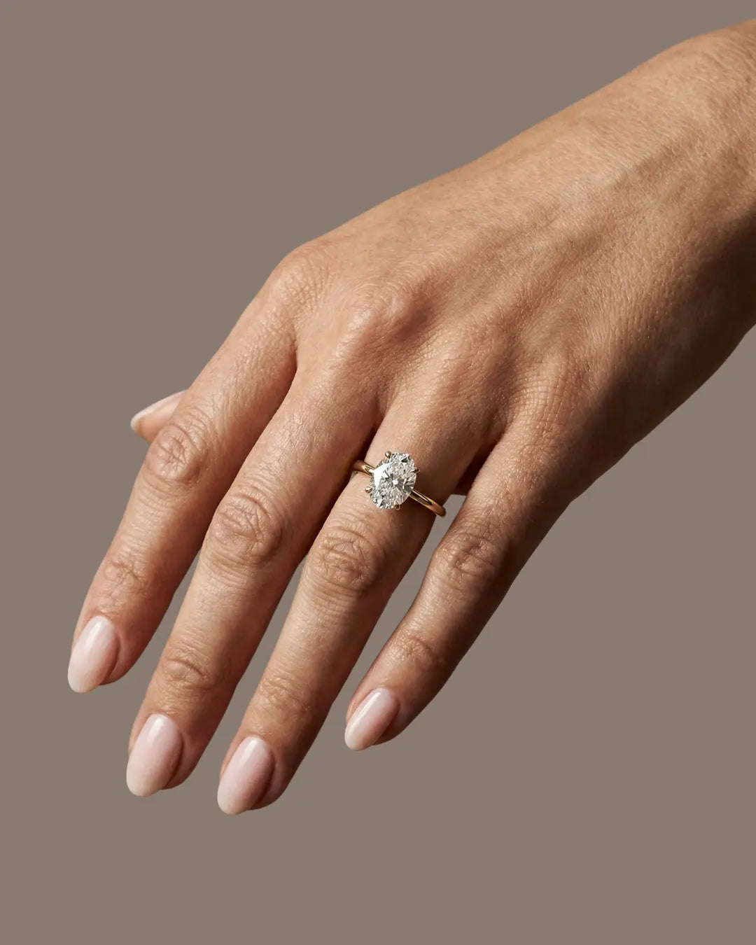 Oval forlovelsesring i gult gull med lab-diamant, vist på hånd