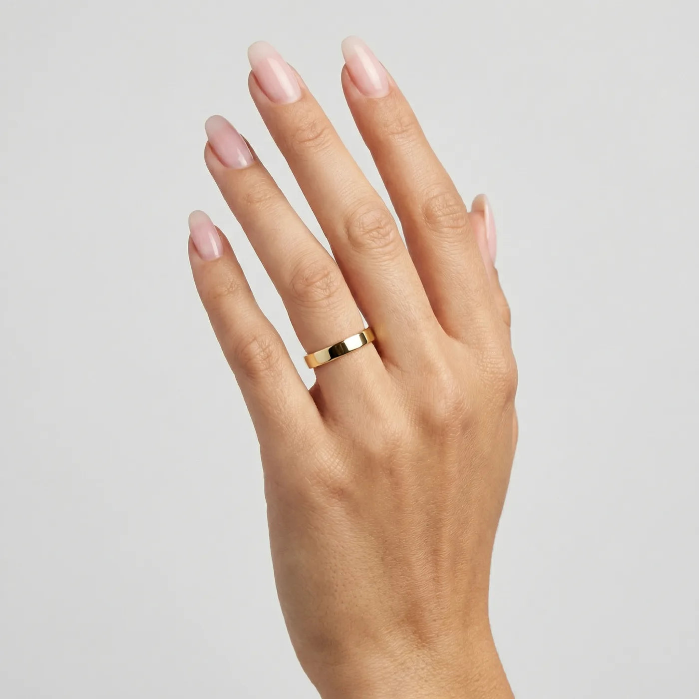 Giftering i flat form 4,5 mm bred i gult gull, vist på hånd. 