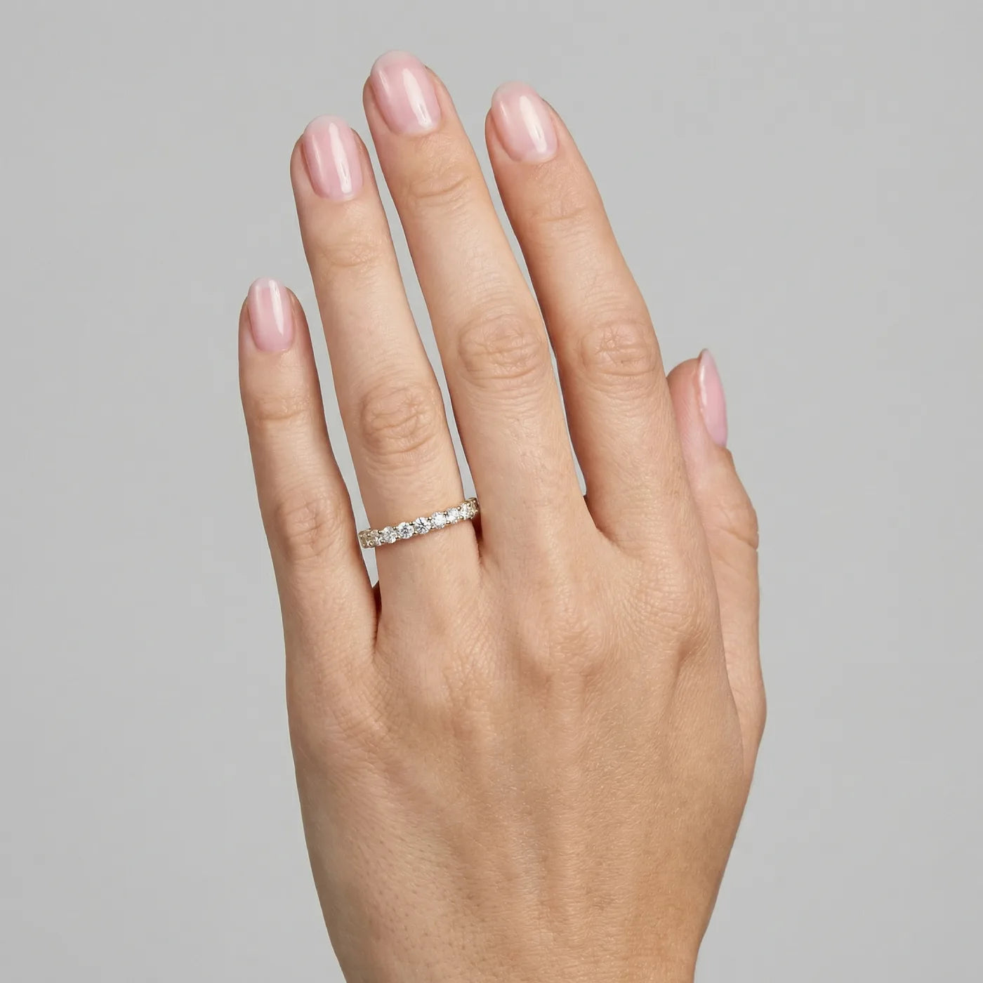 Halv alliansering i gult gull med 0,60 carat diamanter vist på hånden til modell