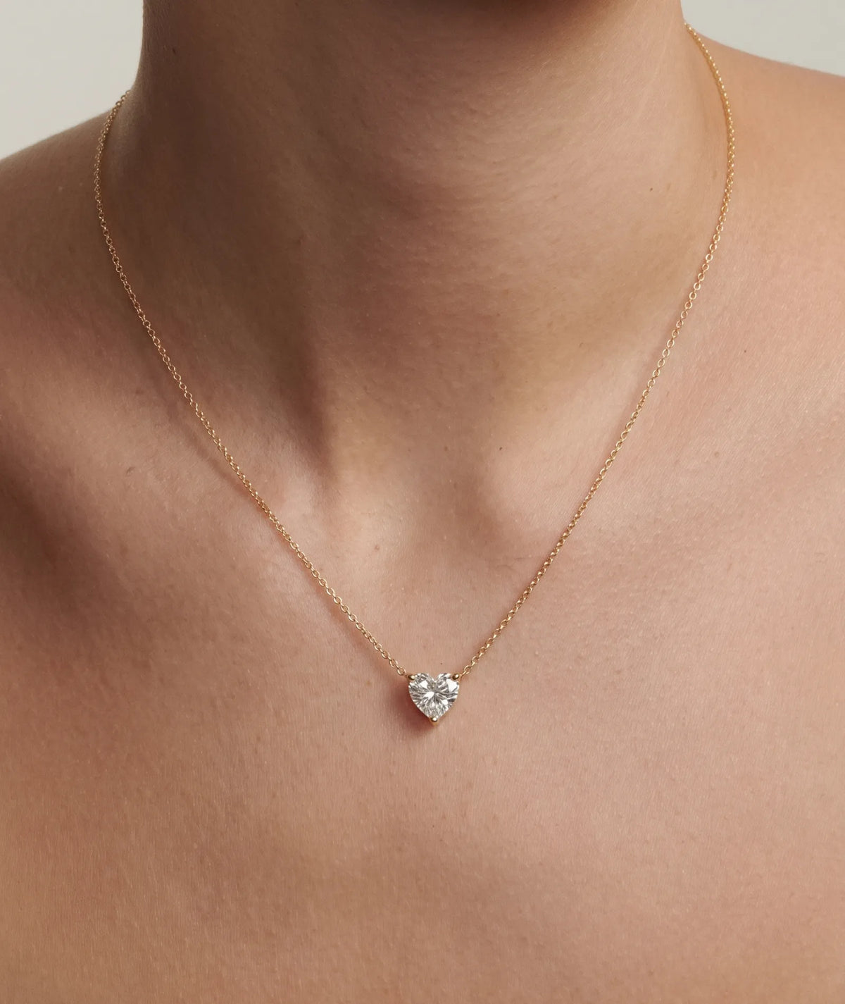 Hjerte formet diamanthalskjede i kloinnfatning, 14K gult gull på modell.