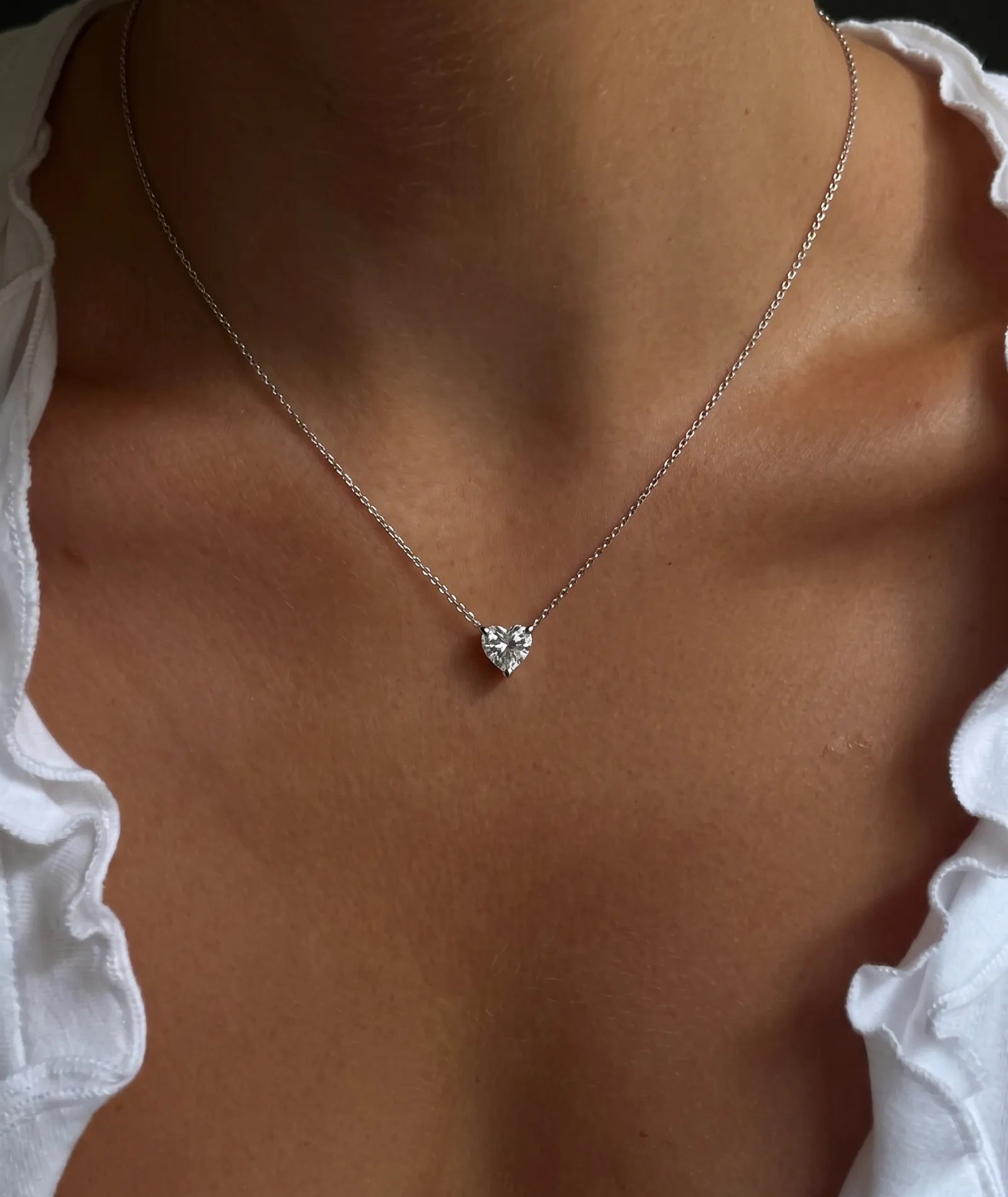 Hjerte formet diamanthalskjede i kloinnfatning, 14K hvitt gull på modell.