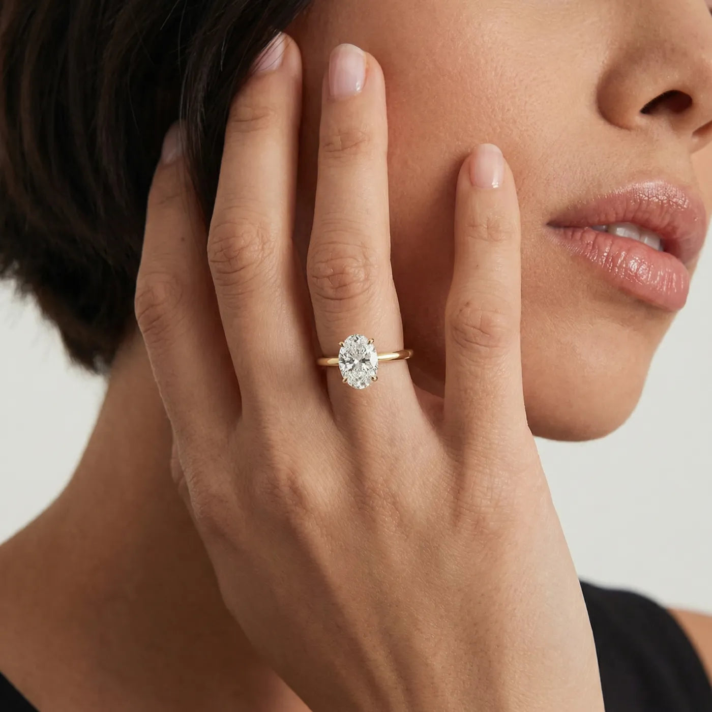 Oval forlovelsesring i gult gull med 1 carat lab diamant vist på modell i naturlig lys