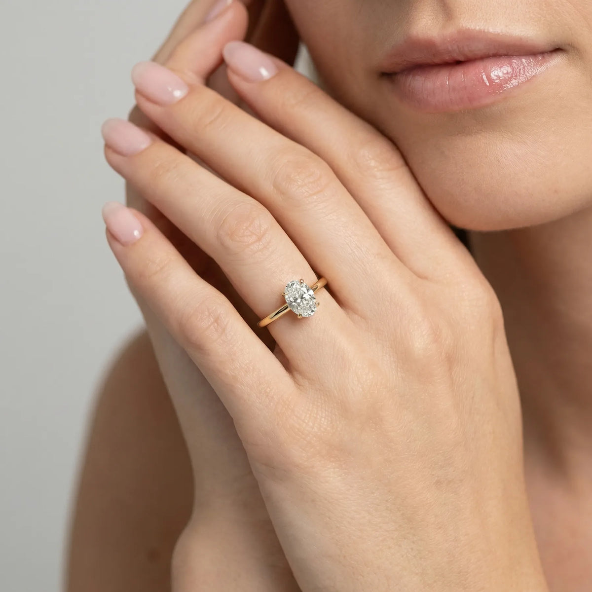 Oval forlovelsesring i gult gull med 1,00 ct lab-diamant. Langstrakt fasong, lav innfatning, hvs på hånden til modell. 
