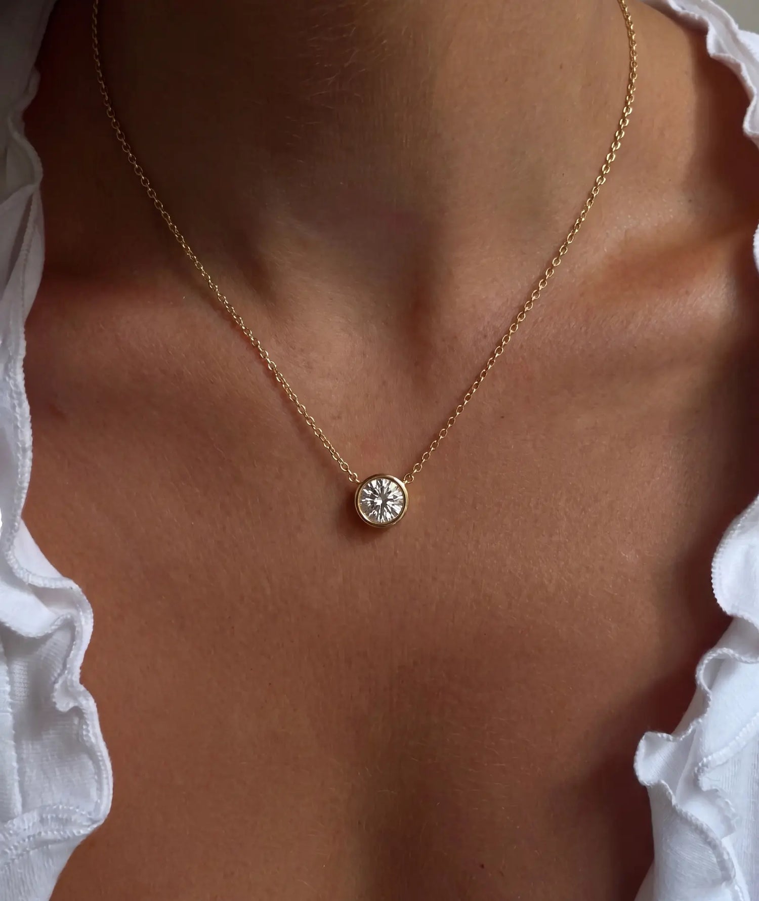 Rund diamanthalskjede i bezelinnfatning, 14K gult gull på modell