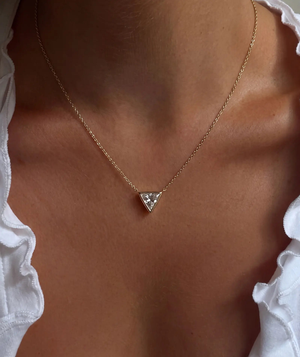 Triangel diamanthalskjede i bezelinnfatning, 14K gult gull på modell.