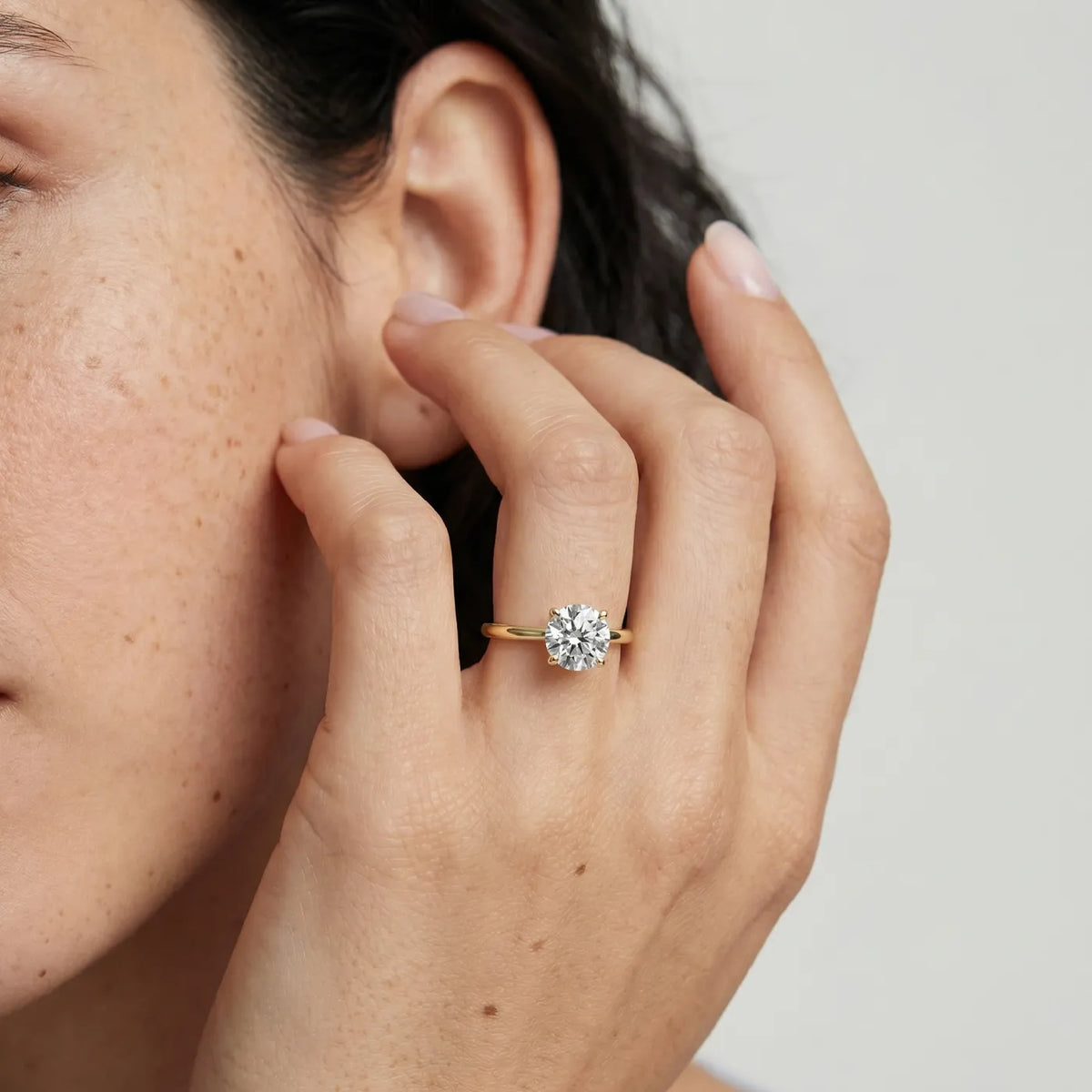 1 ct tynn diamantring i gult gull med lab diamant vist på modell i naturlig lys