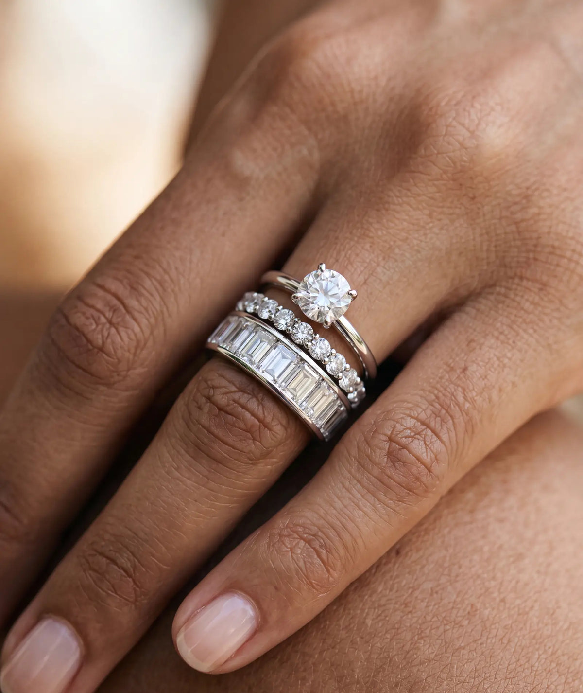 tynn diamtring med 0,50 carat i hvitt gull på finger sammen med en evighetsring med runde diamanter og en emerald cut med bazel nfattning i hvitt gull fra hartwell
